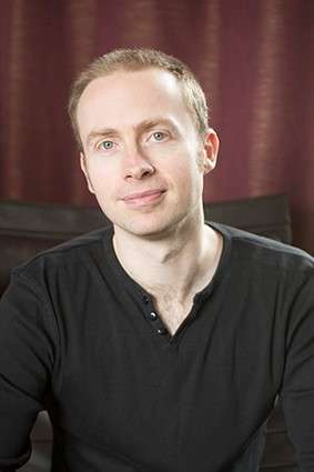 Peter Newman - A fair-haired man wearing a black top smiles towards the camera