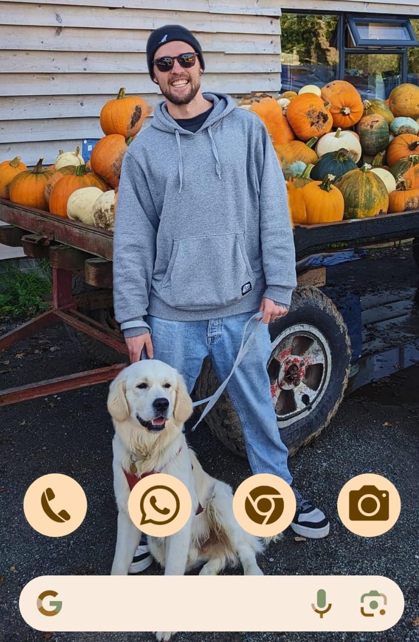 Ben Eaton with his dog, standing in front of a barrow full of pumpkins