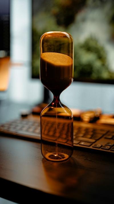 An hourglass on a table next to a keyboard