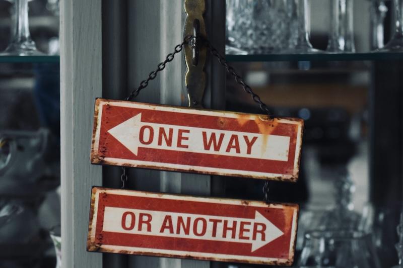 Two signs hanging: one says "one way", the other says "or another"
