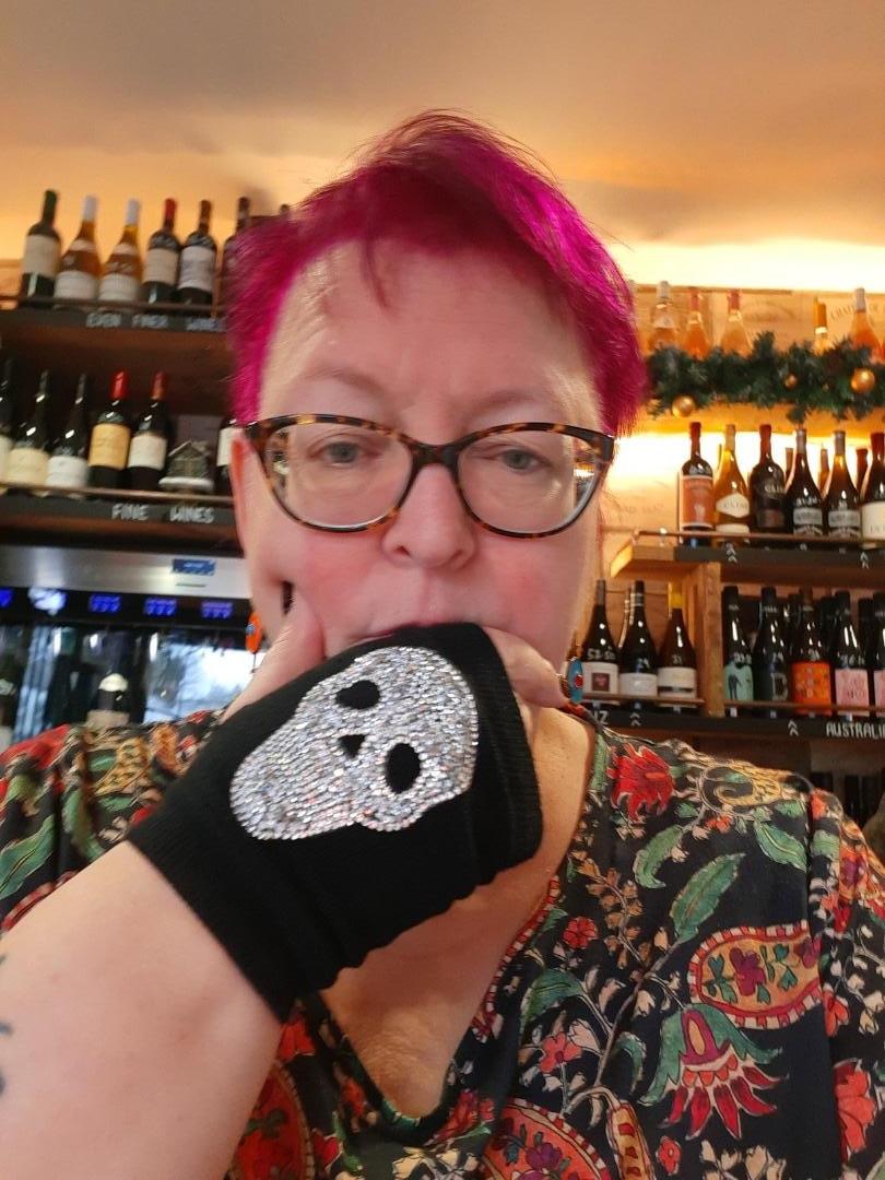 Author Nicolette M. Ward sits in front of a stocked bar