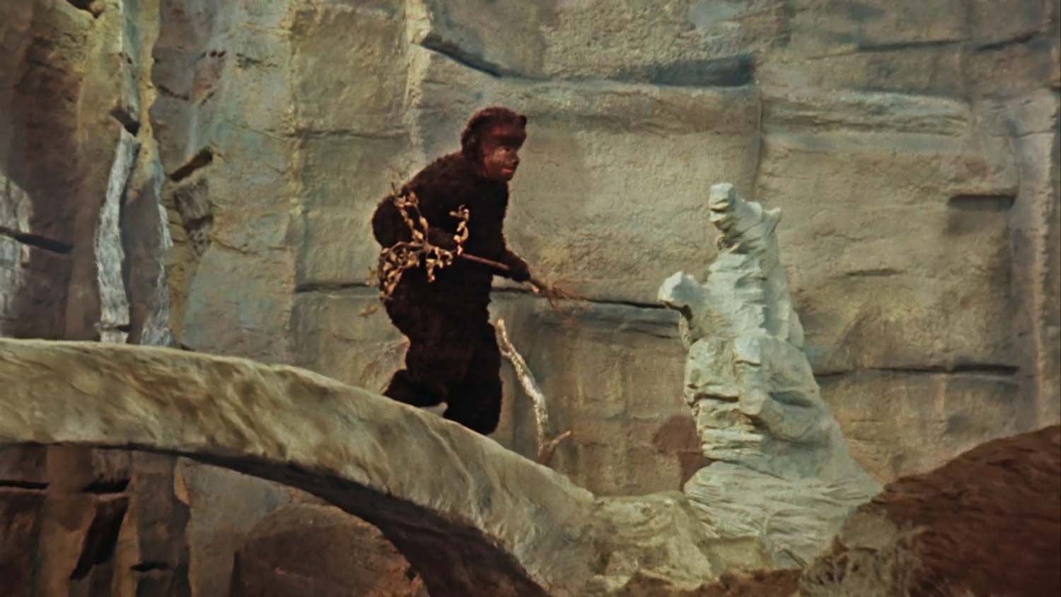 A still from the Singing Ringing Tree depicting a bear, played by a man in a costume, crossing a stone bridge.