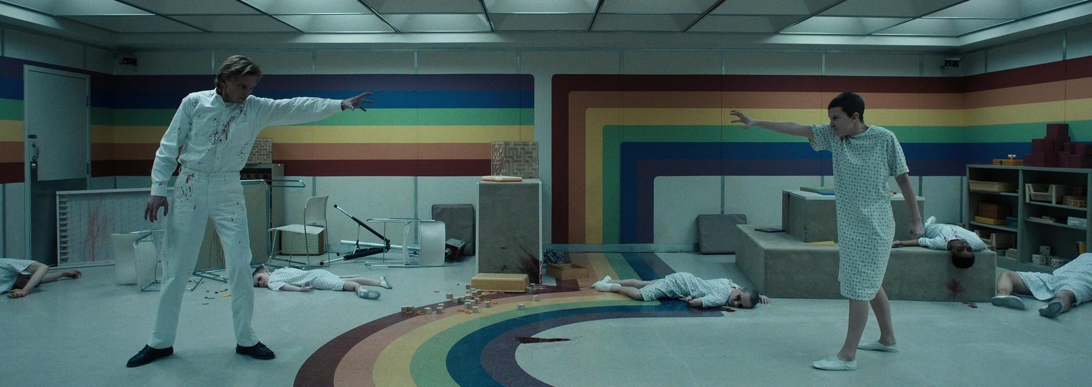 Number One and Number Five face off in ruined hospital gowns in a damaged hospital room