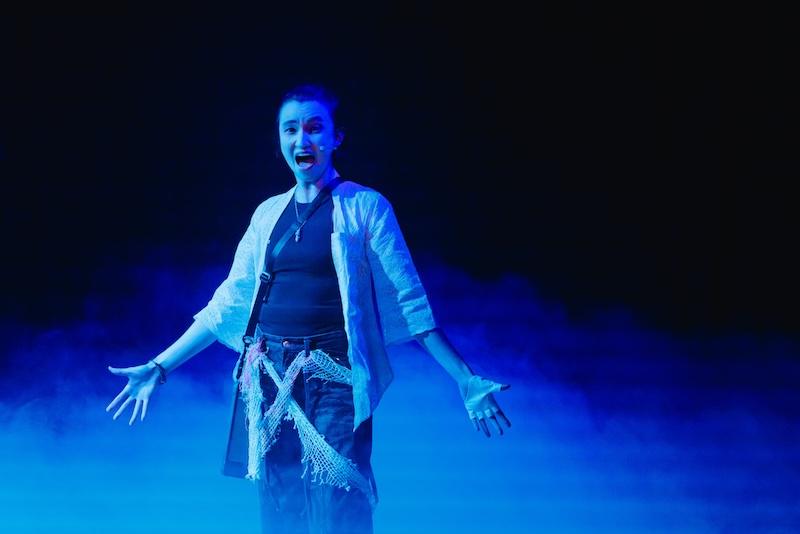 A scene from Asian Pirate Musical shows a performer bathed in blue light