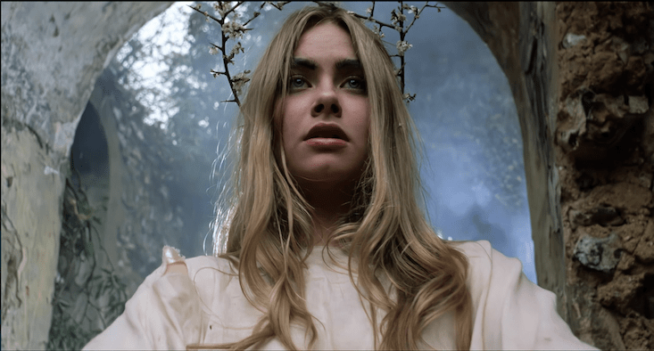 A scene from Blood on Satan's Claw shows a young blonde girl wearing a stick-based crown standing in some ruins
