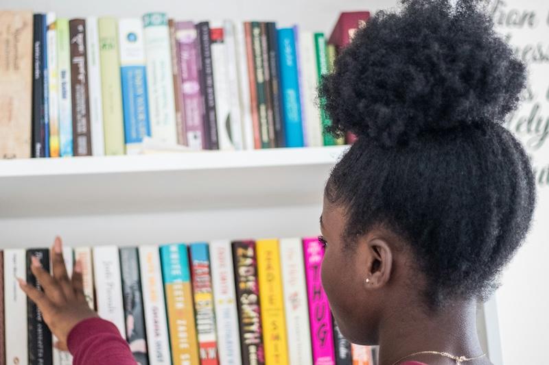 A black girl peruses book shelves