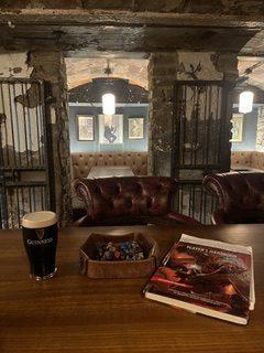 A book and pint of Guinness sit on a table in an old pub