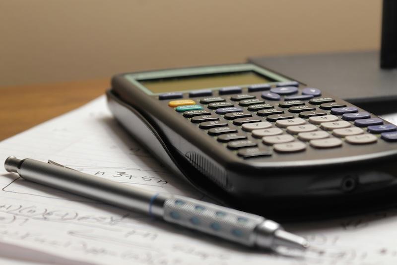 Calculator and pen on top of paper with scribbles