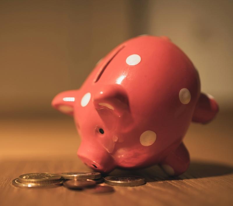A pink piggy bank with coins