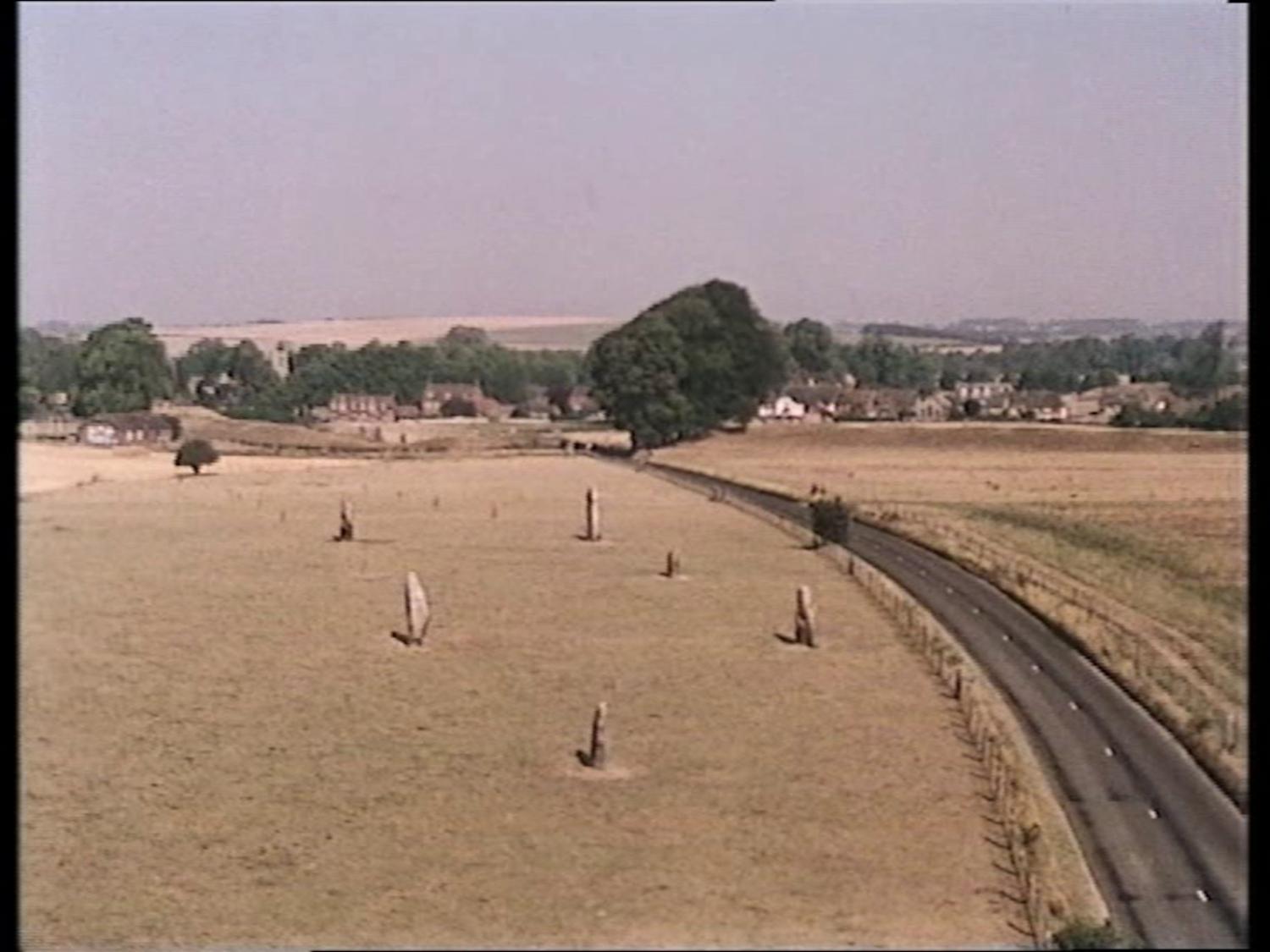 A daytime aerial shot of the Avebury stones with the road on the right.