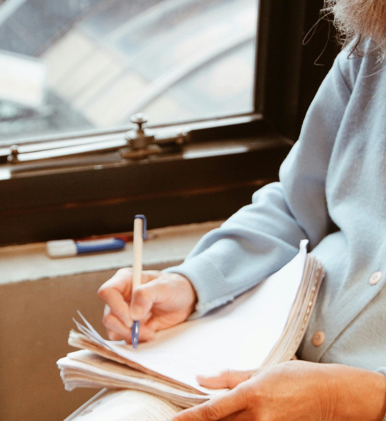 A man annotating a printout or typescript by hand. His face is out of shot, you can just see the edge of his beard.