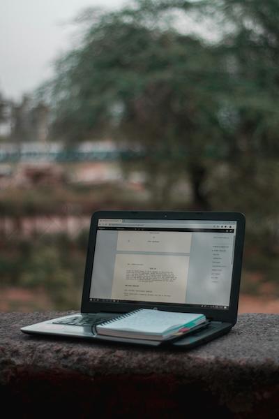 A laptop and notebook sit on a wall outside