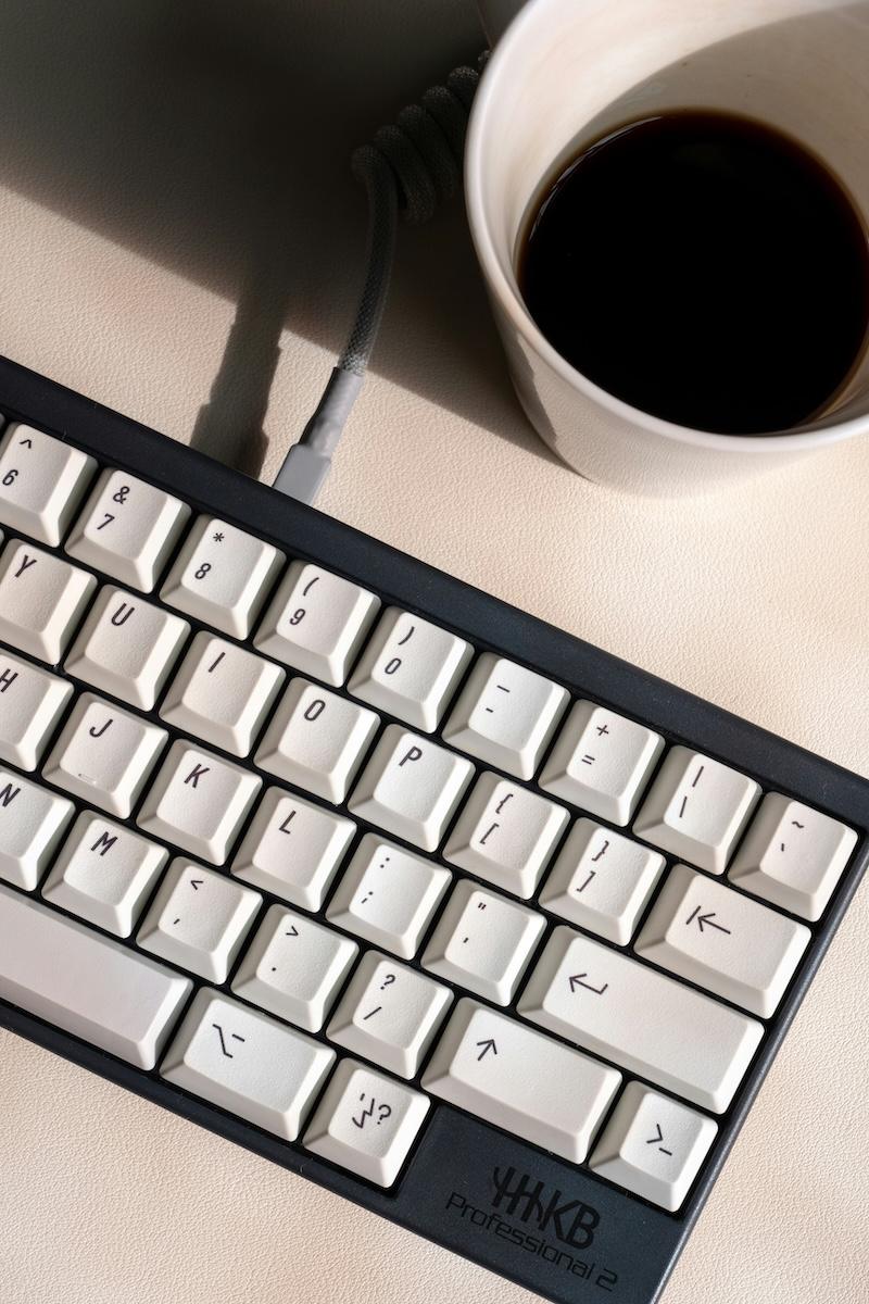 A computer keyboard and coffee cup photographed from above