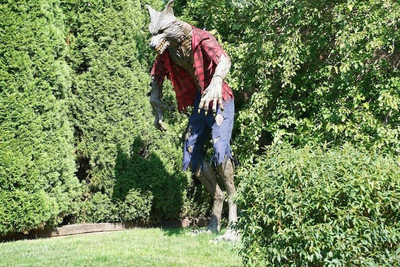 A werewolf statue with ripped clothes stands in a garden